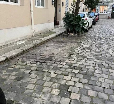 Rue pavée calme avec voitures garées à Paris 16ème.