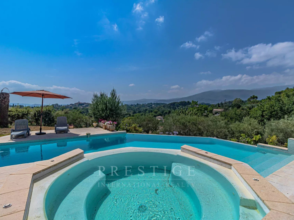 View of the swimming pool and jacuzzi in a villa in Châteauneuf-Grasse, with green landscape in the background.