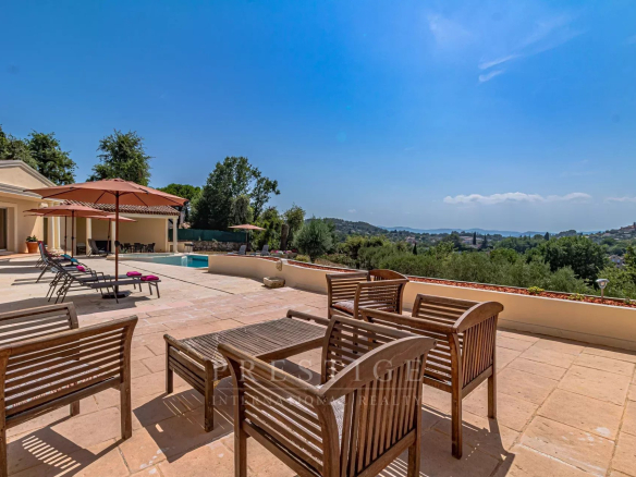 Terrace of a villa in Châteauneuf-Grasse with outdoor furniture and panoramic views of the landscape.