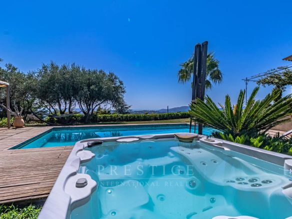 Vue de la piscine et du jacuzzi dans une villa au Tignet, avec des collines en arrière-plan.