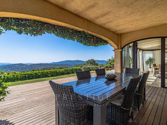 Terrasse d'une villa avec vue panoramique sur la mer et les collines, mobilier en bois
