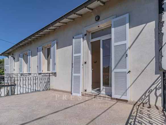 Façade d'une maison à Juan-les-Pins avec balustrade et fenêtres à volets.