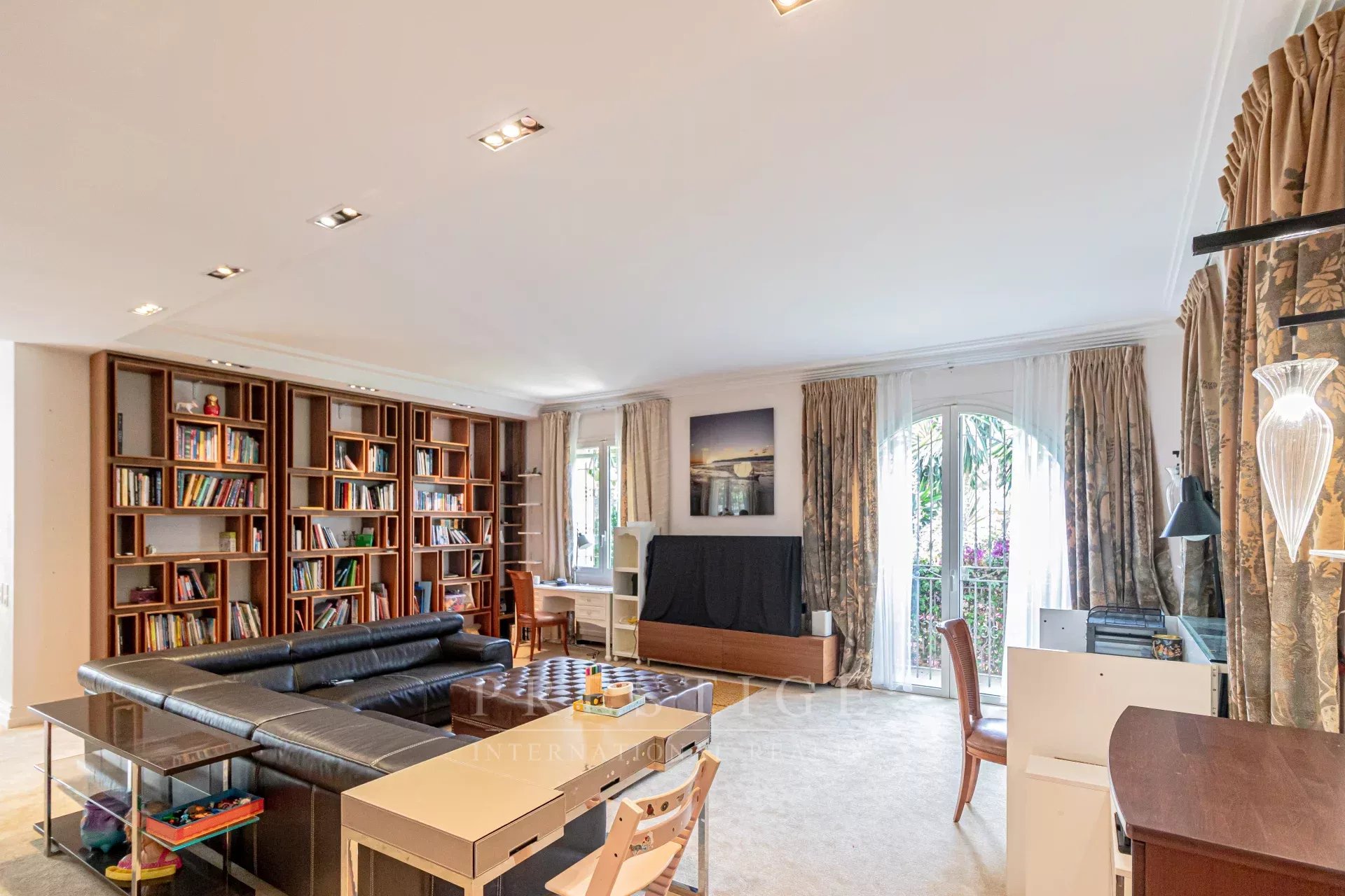 Intérieur d’une villa à Cap d’Antibes Intérieur d'une villa luxueuse à Cap d'Antibes, salon avec bibliothèque et espace de travail.