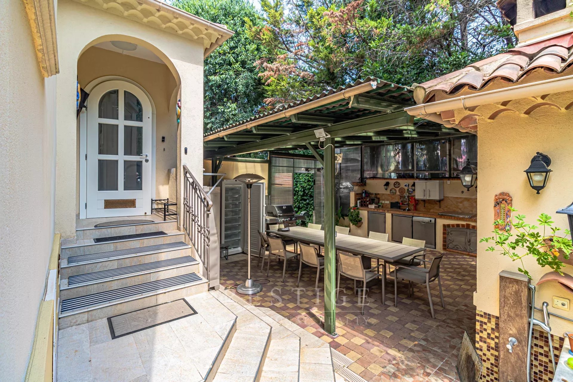 Villa rénovée à Cap d’Antibes Entrée d'une villa rénovée à Cap d'Antibes avec terrasse et cuisine extérieure.