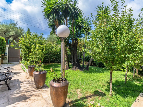 Jardin d'une villa luxueuse au Cap d'Antibes avec des plantes et des lampadaires.
