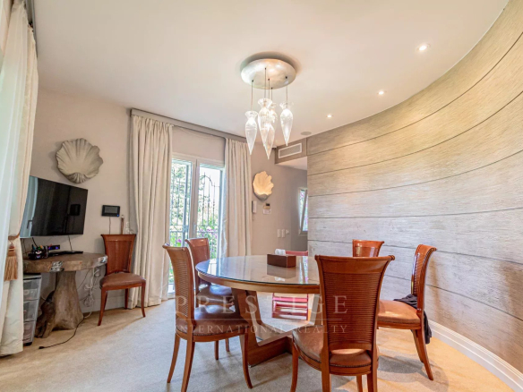 Salle à manger d'une villa rénovée à Cap d'Antibes avec table ronde et chaises en rotin.