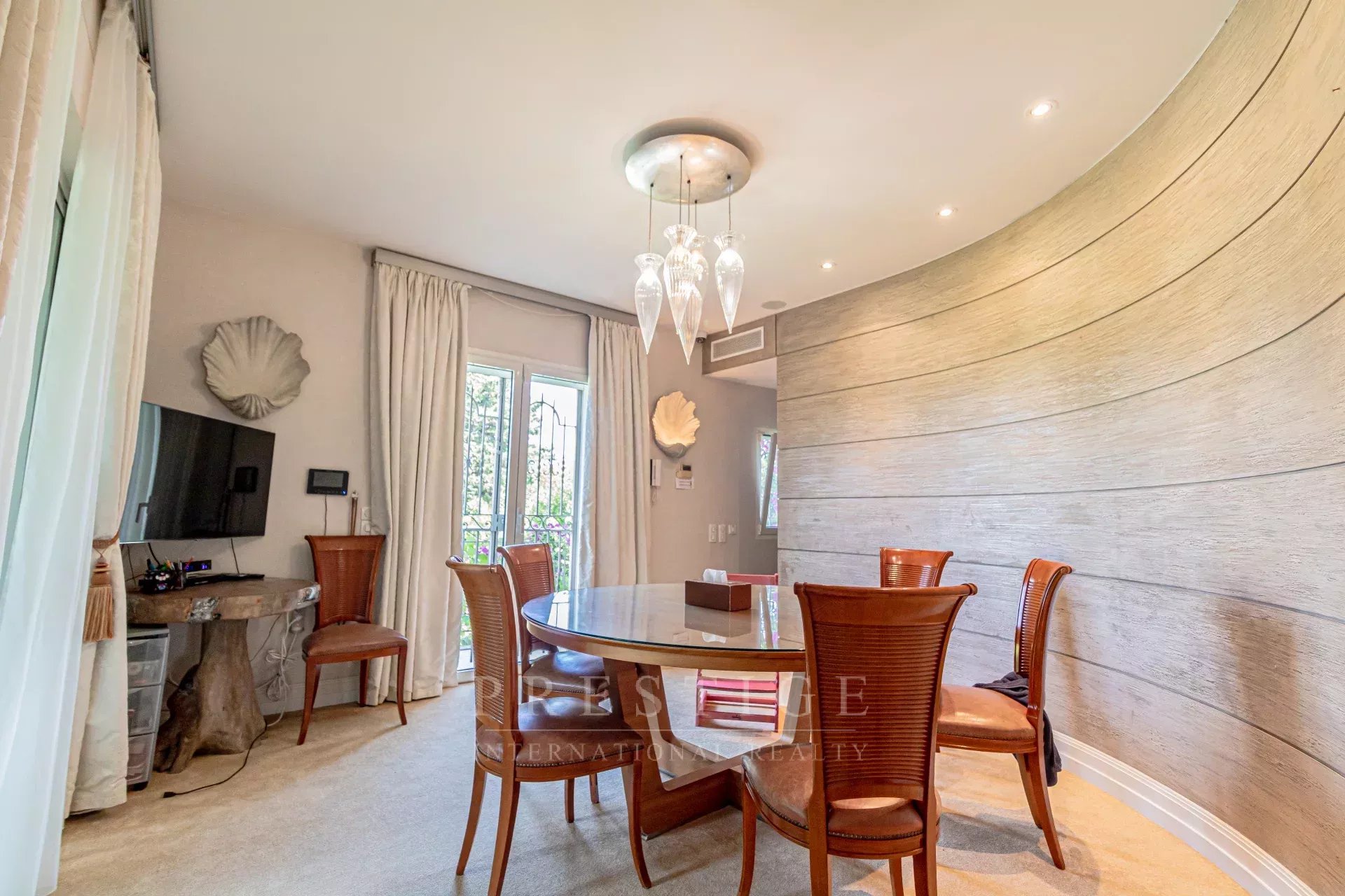 Salle à manger moderne à Cap d’Antibes Salle à manger d'une villa rénovée à Cap d'Antibes avec table ronde et chaises en rotin.