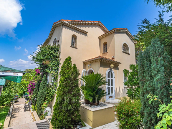 Villa luxueuse à Cap d'Antibes, entourée de verdure, avec jardin et terrasse.