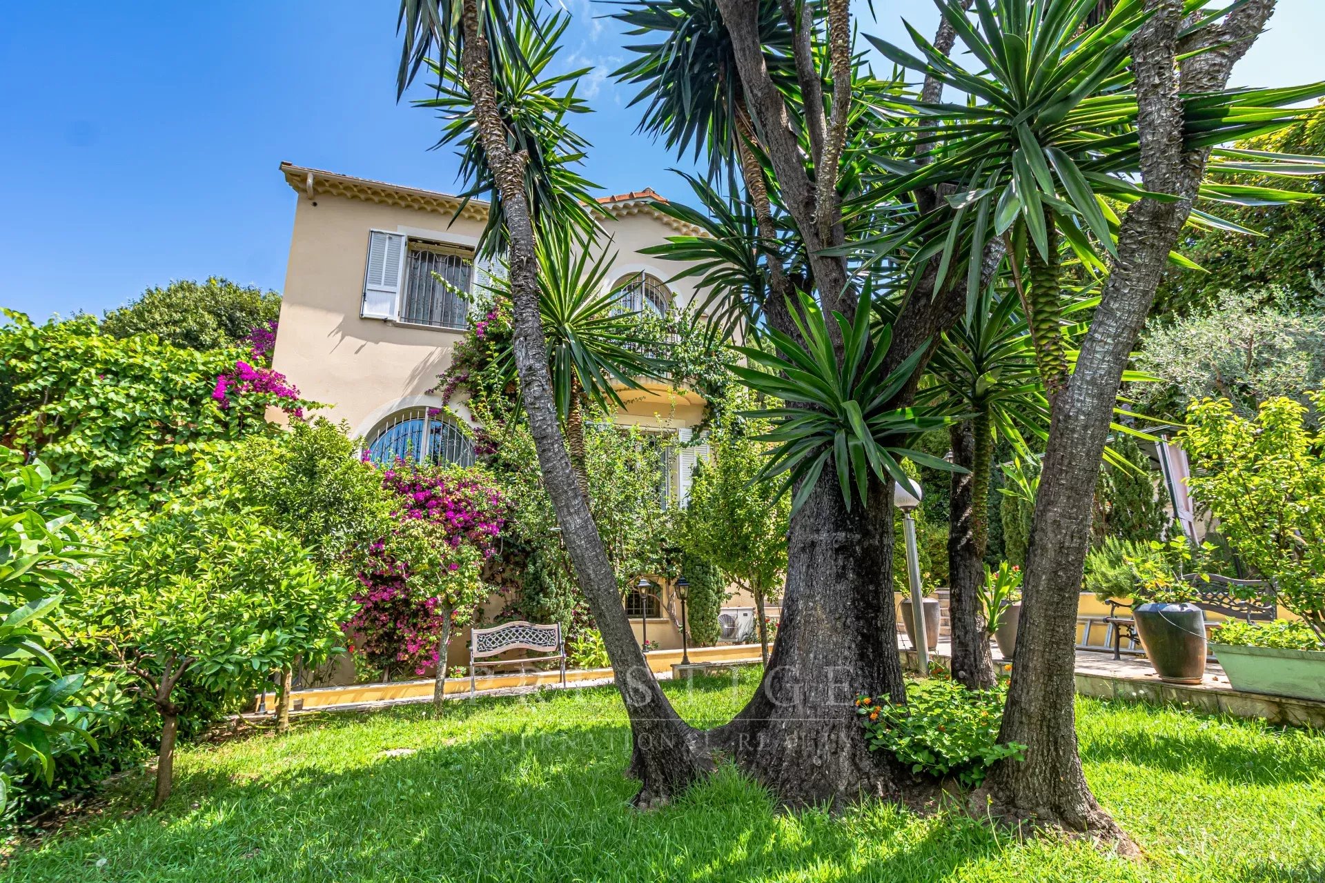 Villa rénovée à Cap d’Antibes Villa luxueuse à Cap d'Antibes entourée de verdure et de palmiers.