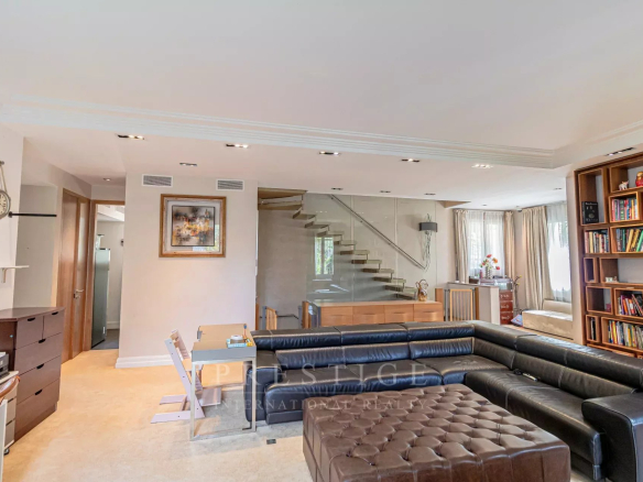 Intérieur d'une villa luxueuse à Cap d'Antibes, salon spacieux avec canapé et escalier moderne.