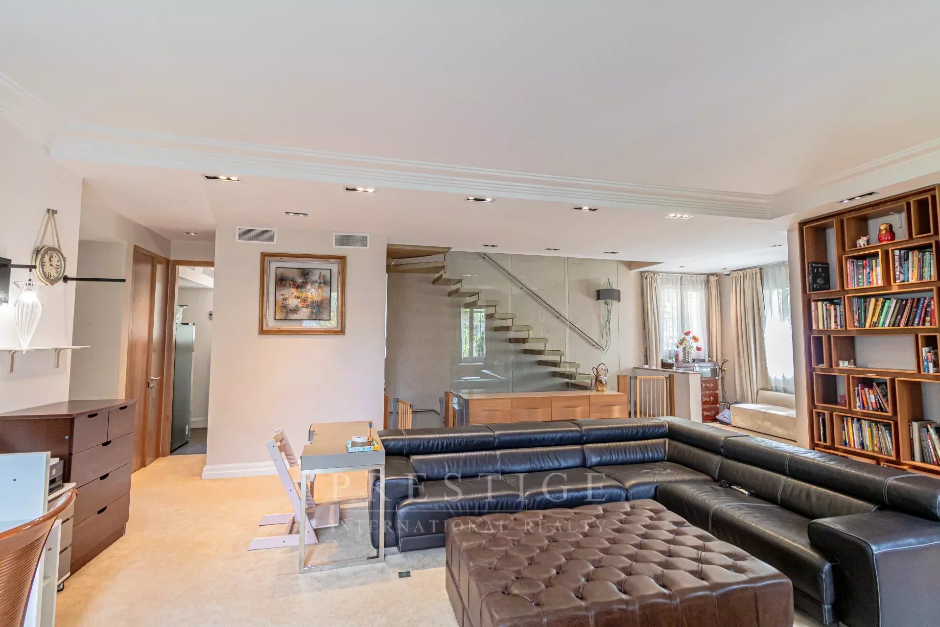 Intérieur d’une villa à Cap d’Antibes Intérieur d'une villa luxueuse à Cap d'Antibes, salon spacieux avec canapé et escalier moderne.