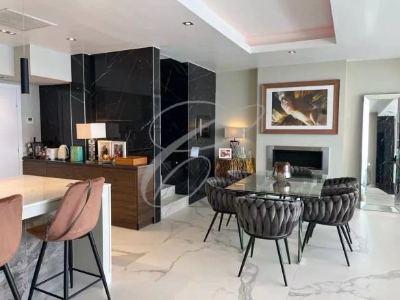 Open-concept living area with a glass dining table and tufted gray chairs, black marble wall feature, and marble floors.