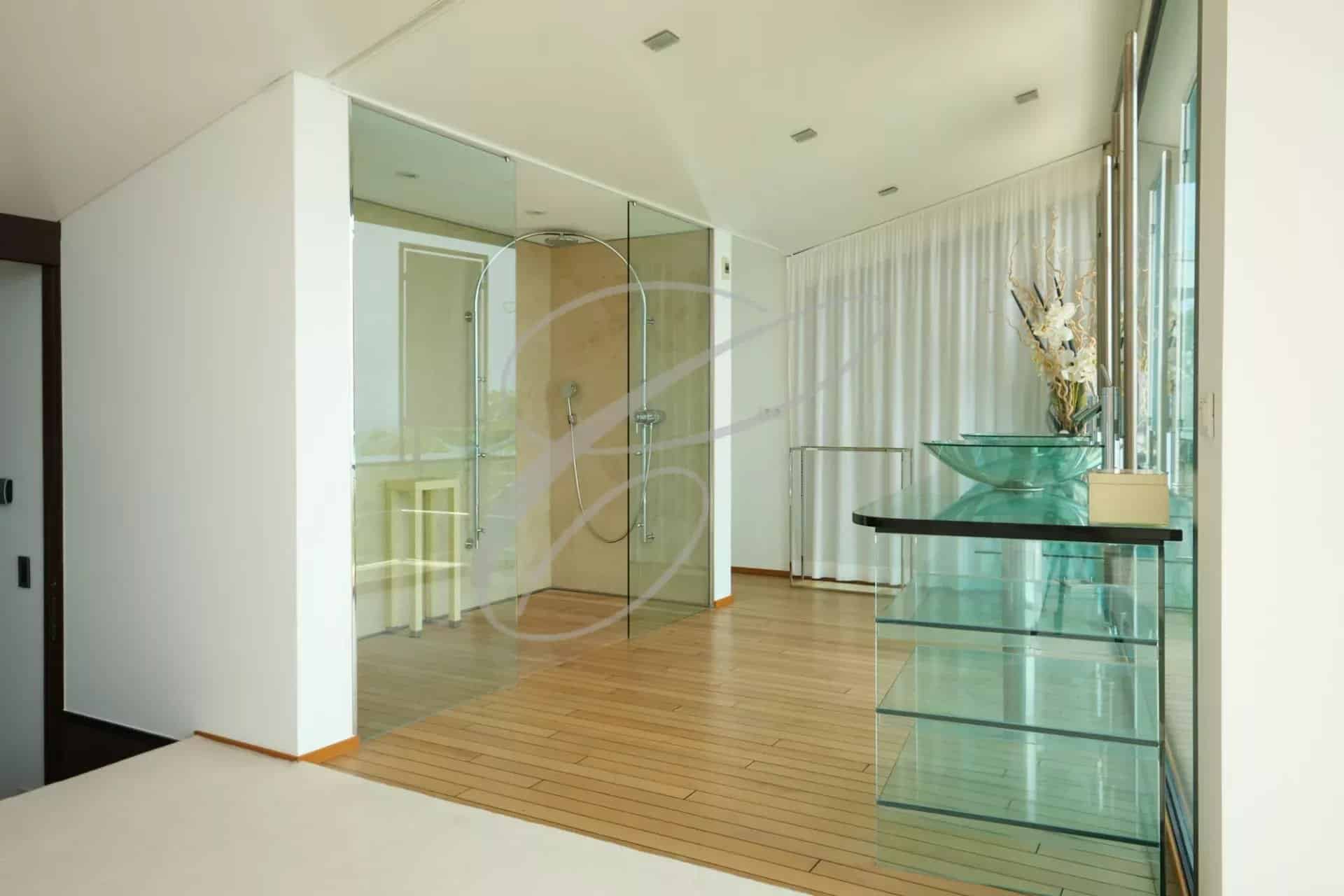 Intérieur d'une villa contemporaine avec sol en bois et salle de bain en verre.