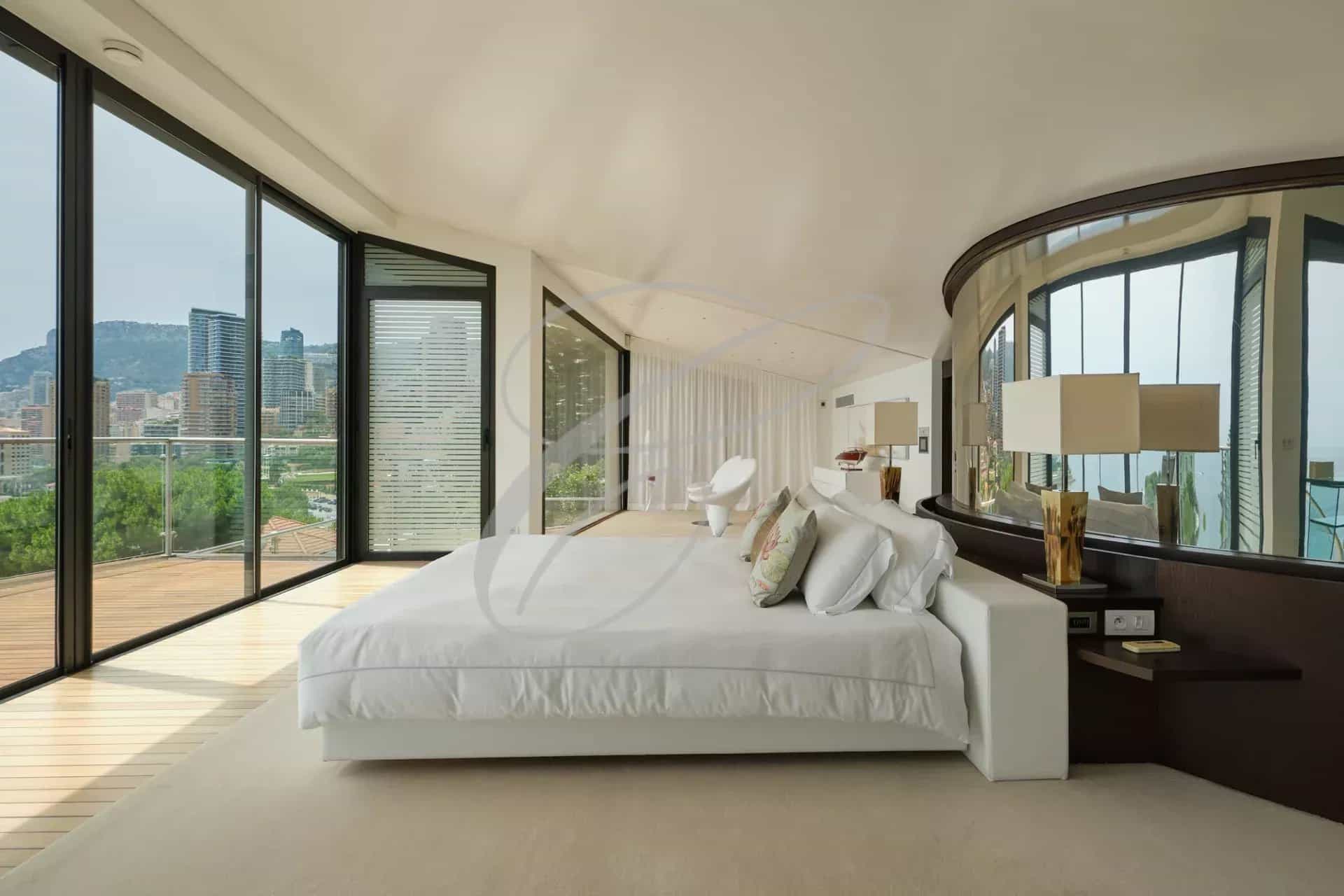 Chambre moderne avec vue sur la mer et la ville, grande fenêtre et lit king-size.