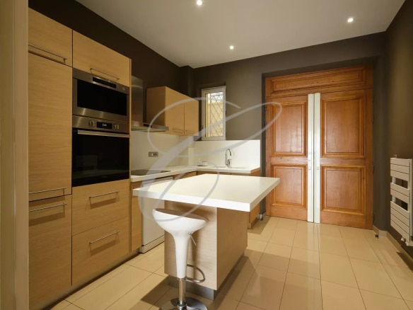 Modern kitchen in a spacious apartment in Beausoleil, with wooden furniture and a bar.