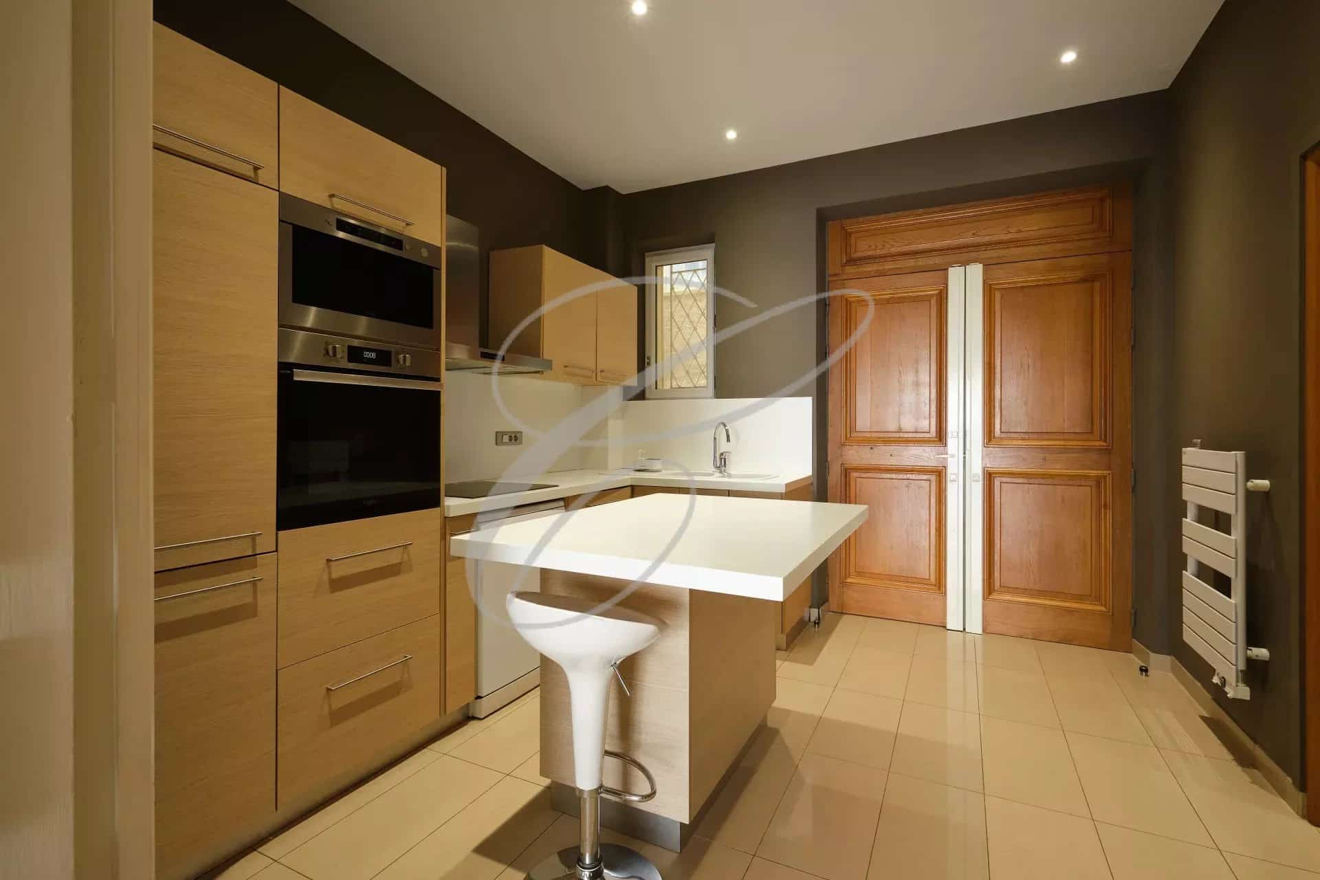 Modern kitchen in a spacious apartment in Beausoleil, with wooden furniture and a bar.