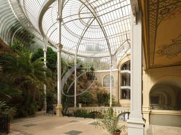 Interior of a Belle Époque palace in Beausoleil with a glass roof and greenery