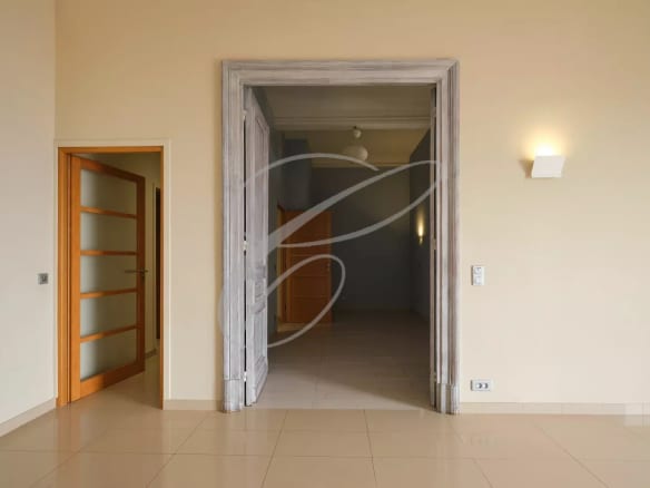 Interior of a spacious apartment in Beausoleil, with light walls and wooden doors.