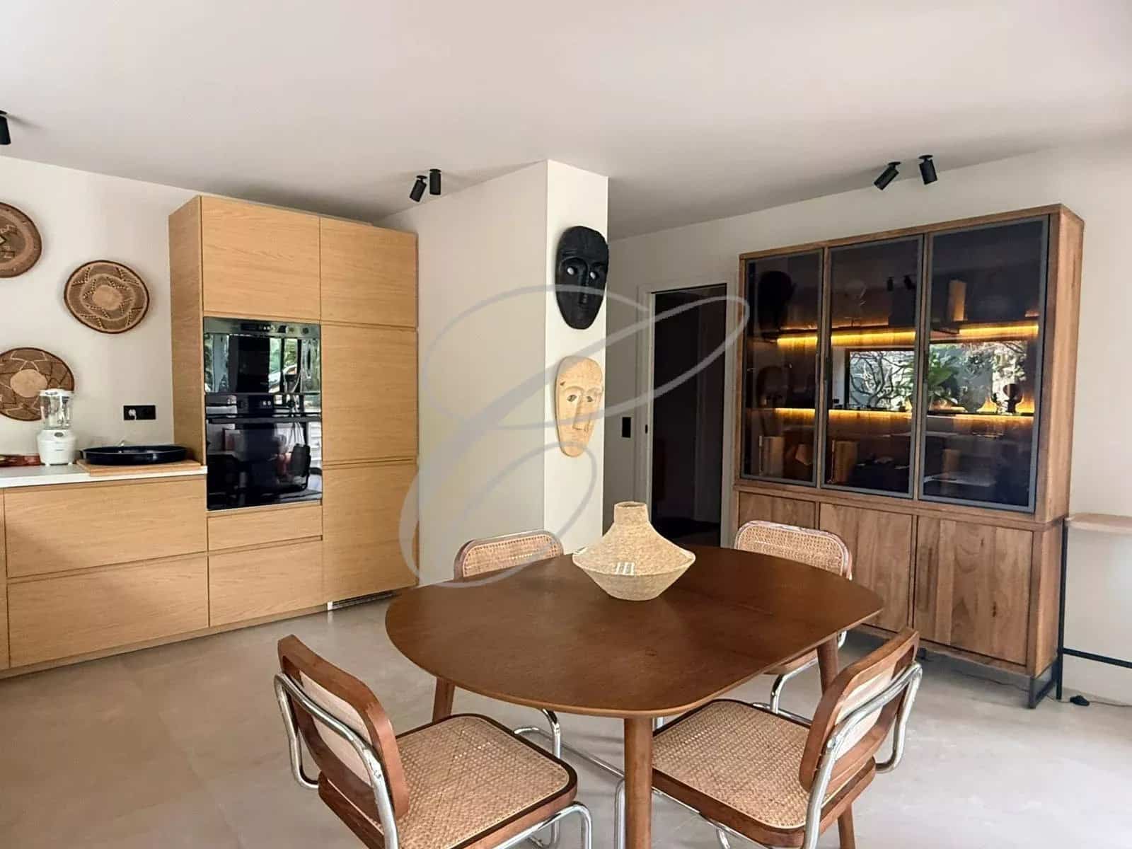 Intérieur d'un appartement rénové avec salle à manger, cuisine équipée et décoration moderne.