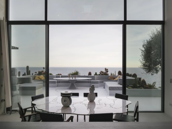 Interior of a contemporary villa with sea view, round table and furnished outdoor space.