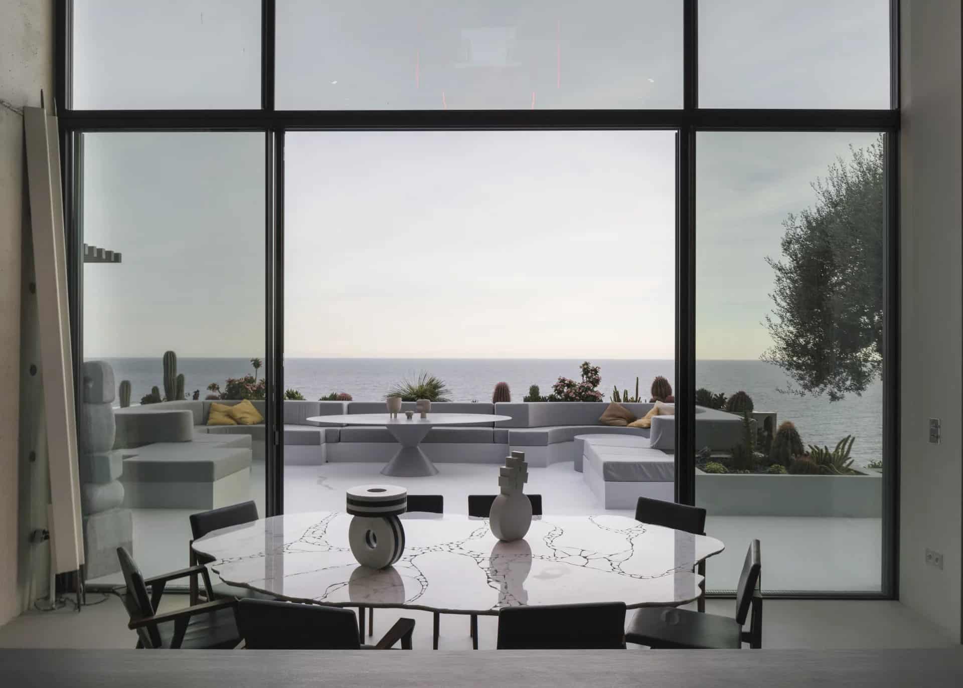 Interior of a contemporary villa with sea view, round table and furnished outdoor space.