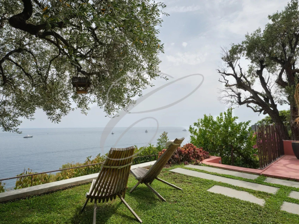 Sea view from a contemporary villa in Roquebrune-Cap-Martin with sun loungers and garden.
