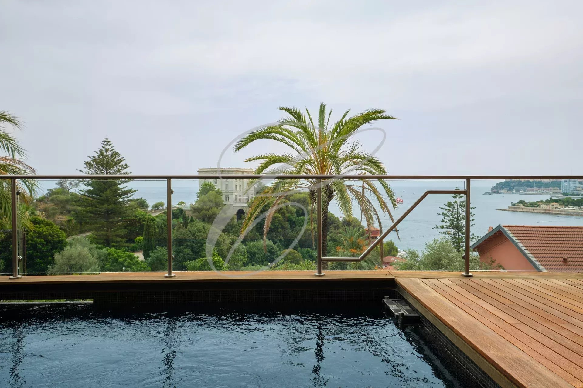 Vue depuis une villa contemporaine avec piscine, palmiers et mer en arrière-plan à Roquebrune-Cap-Martin.