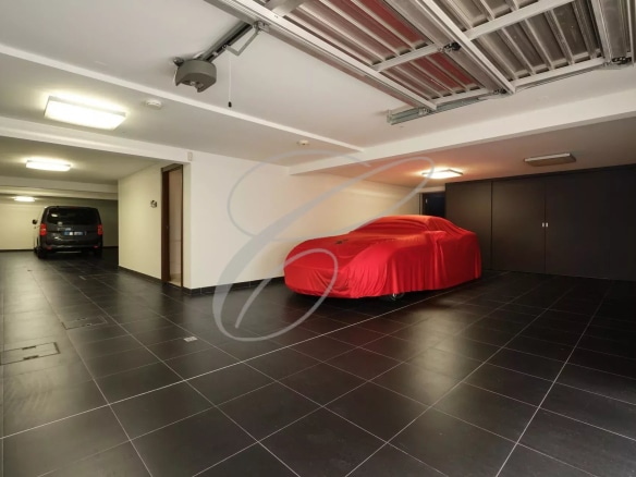 Garage spacieux avec une voiture recouverte et un espace de stationnement à Roquebrune-Cap-Martin.