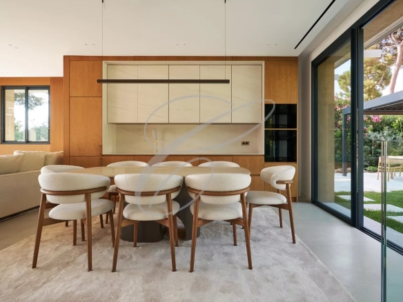 Interior of a luxury villa with dining room and fully equipped kitchen, overlooking the garden.