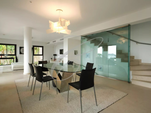 Intérieur d'une villa contemporaine à Roquebrune-Cap-Martin avec salle à manger et escalier en verre.