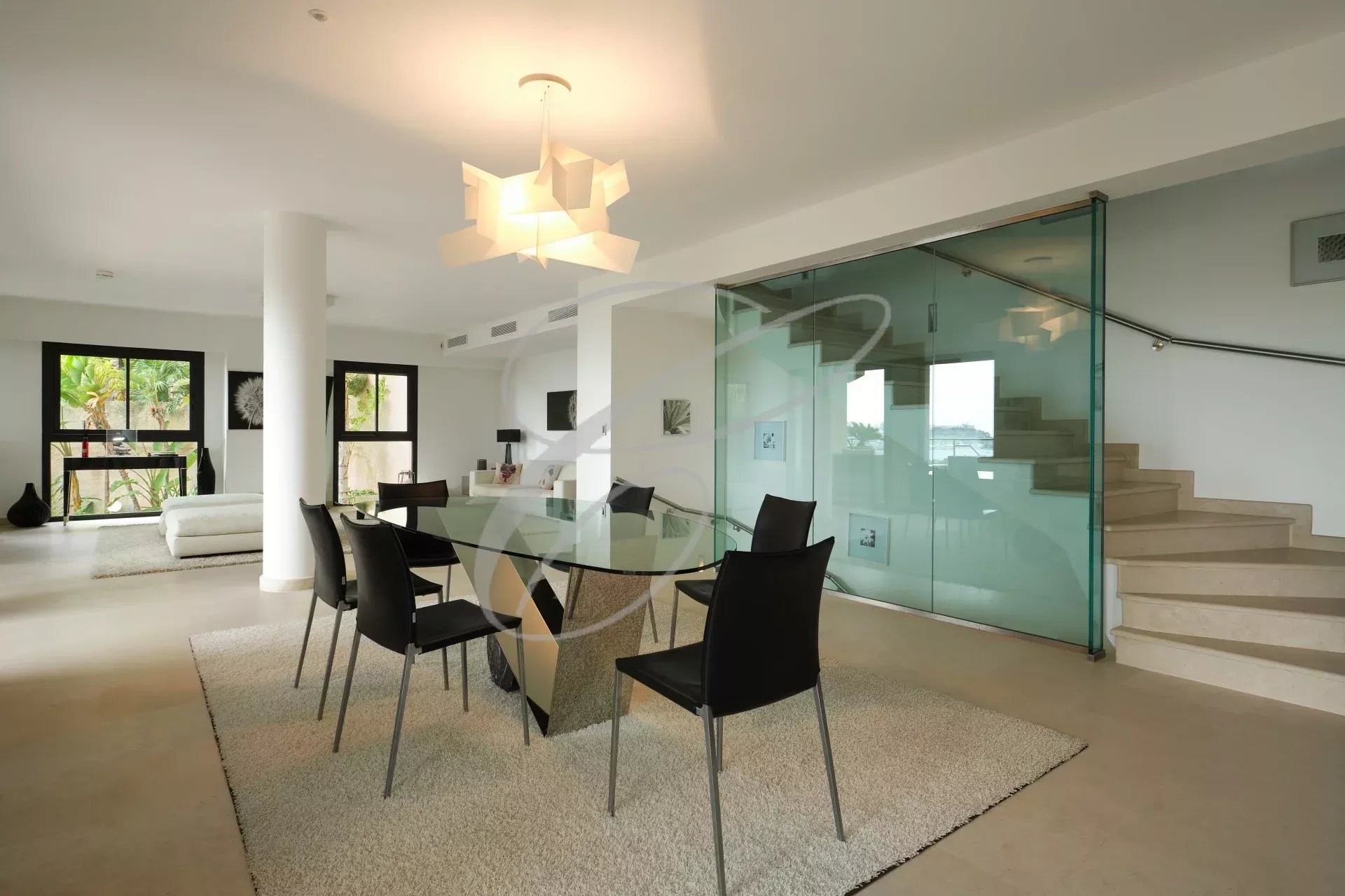 Intérieur d'une villa contemporaine à Roquebrune-Cap-Martin avec salle à manger et escalier en verre.