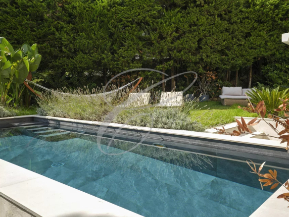 Swimming pool in a private garden with plants and relaxation areas.