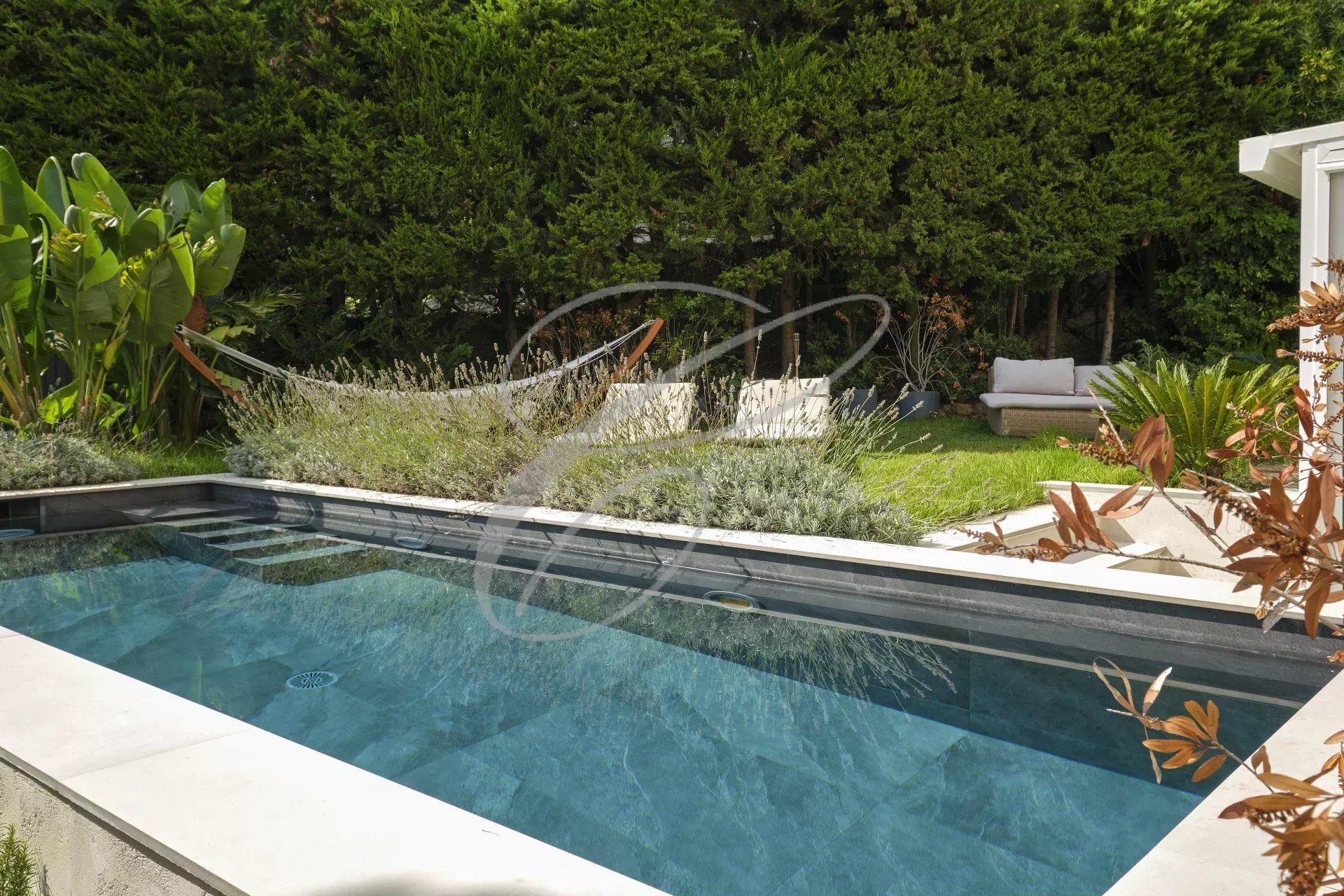 Swimming pool in a private garden Swimming pool in a private garden with plants and relaxation areas.