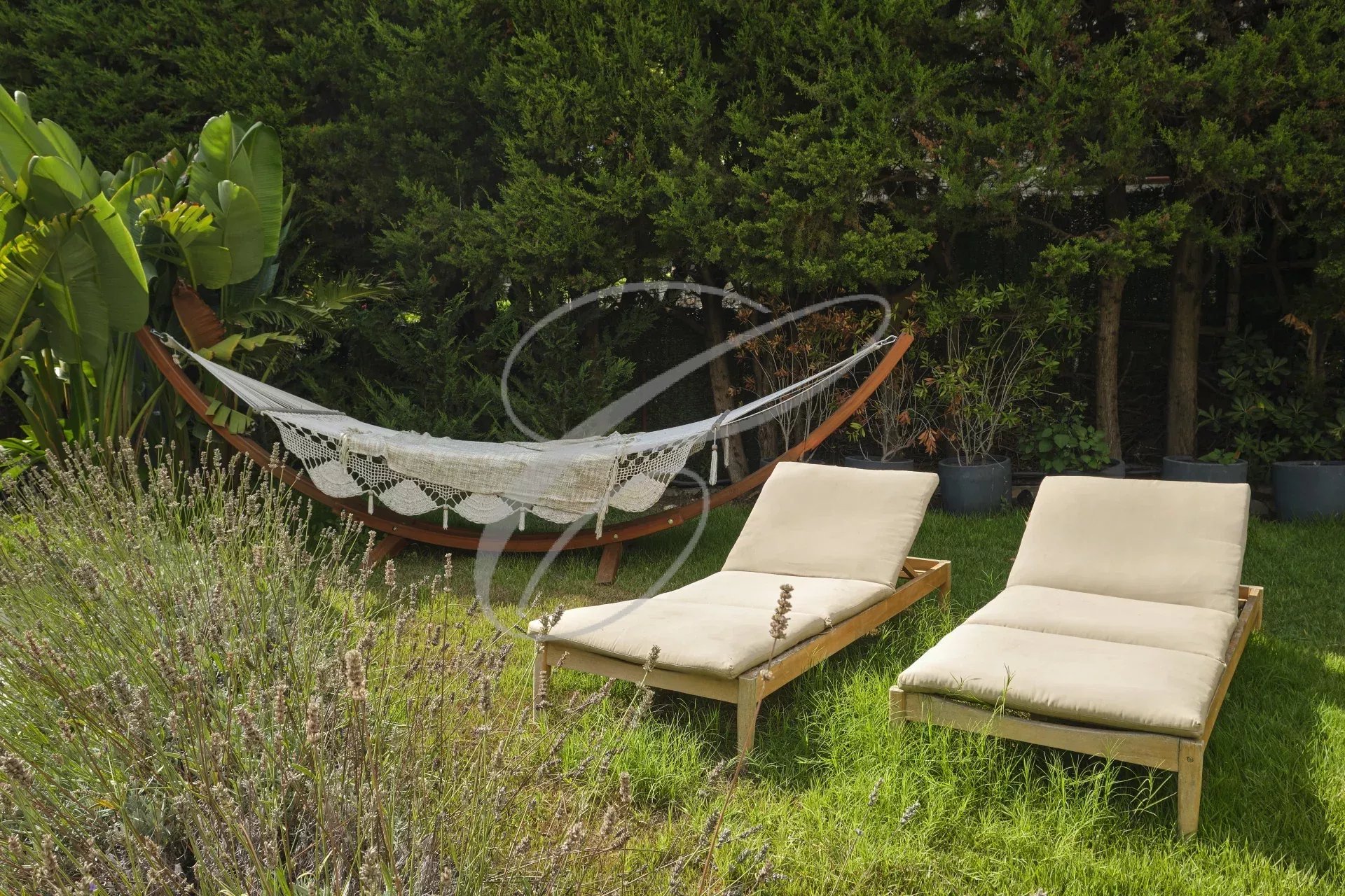 Private garden with sun loungers and hammock Outdoor space of an apartment with deckchairs and hammock in a green garden.