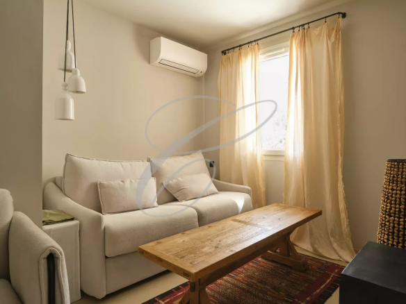 Living room of a renovated apartment with sofa and coffee table, lit by a window.