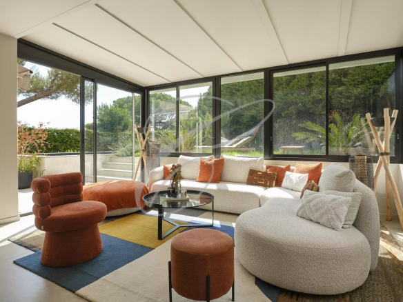 Bright living room of a renovated apartment with windows overlooking a garden, modern and colorful furniture.