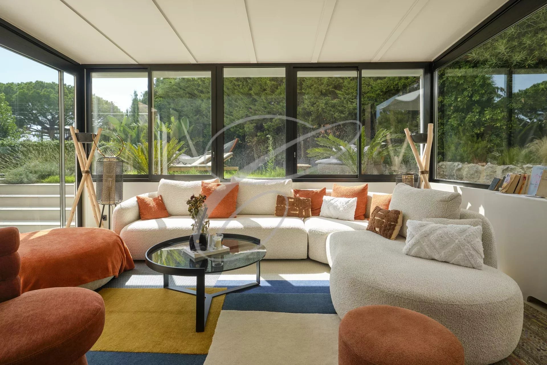 Living room of a renovated apartment in Roquebrune-Cap-Martin Bright living room with sofa and coffee table, windows overlooking a garden.
