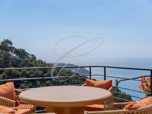 Vue panoramique sur la mer depuis une terrasse avec mobilier de jardin.