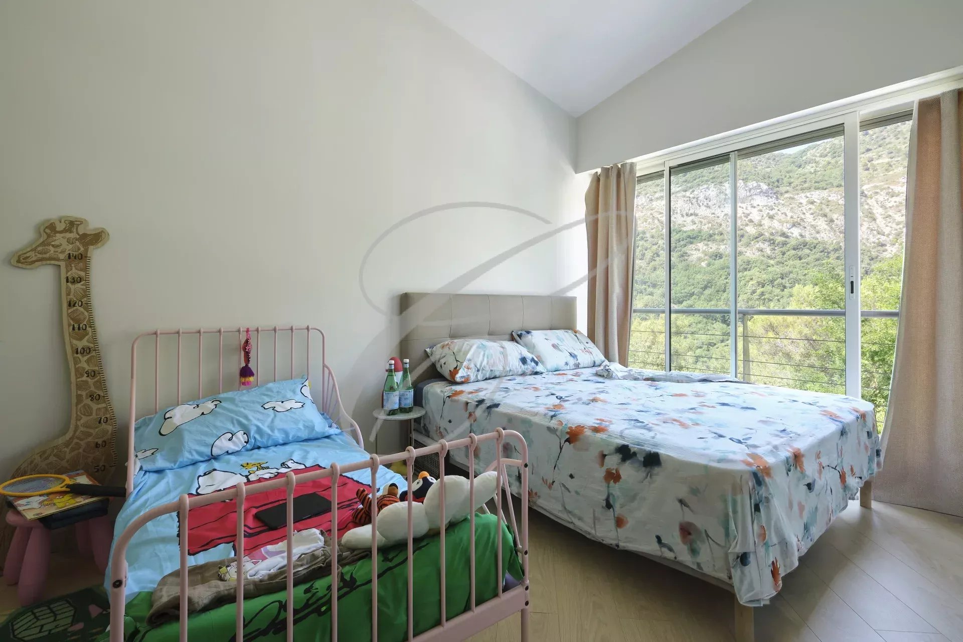 Chambre de villa moderne Chambre d'une villa moderne avec lit double et lit bébé, fenêtres donnant sur la nature.