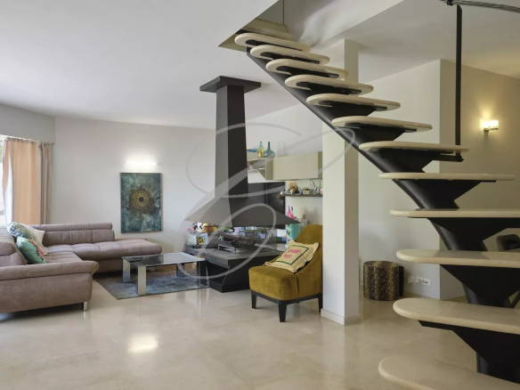 Intérieur d'une villa moderne avec salon, escalier design et décoration contemporaine.