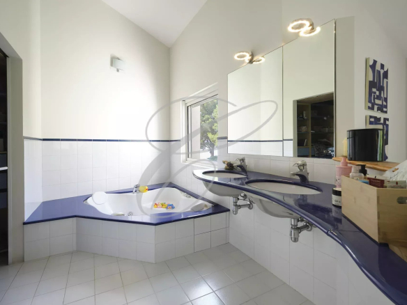 Salle de bains moderne avec baignoire et double vasque dans une villa.