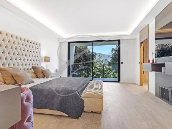 Chambre moderne avec lit king size et vue sur un jardin paysager.