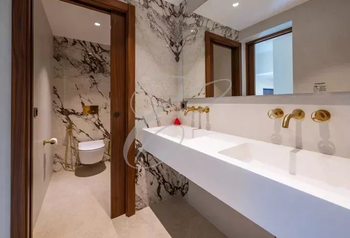 Salle de bains moderne avec lavabo double et toilettes, décorée de marbre.