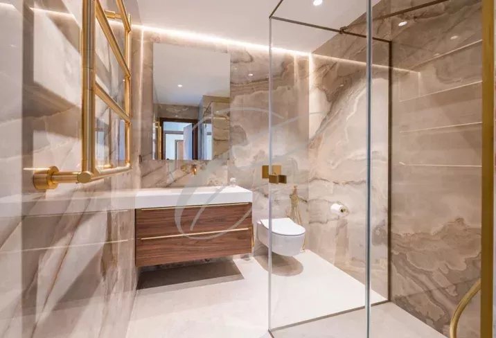 Salle de bains moderne avec douche en verre et meuble en bois dans une villa contemporaine.