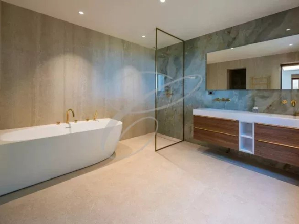 Salle de bains moderne avec baignoire et meuble double vasque, murs en pierre.