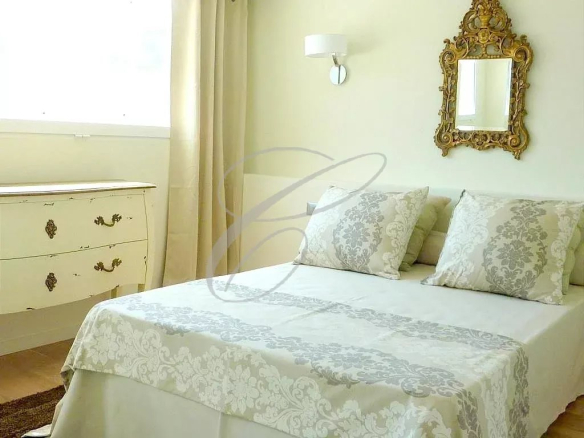 Chambre d'une villa à Èze avec lit double, décoration élégante et miroir ancien.