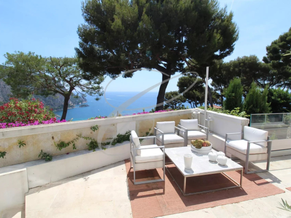Terrasse d'une villa avec vue sur la mer à Èze, mobilier moderne et plantes environnantes.