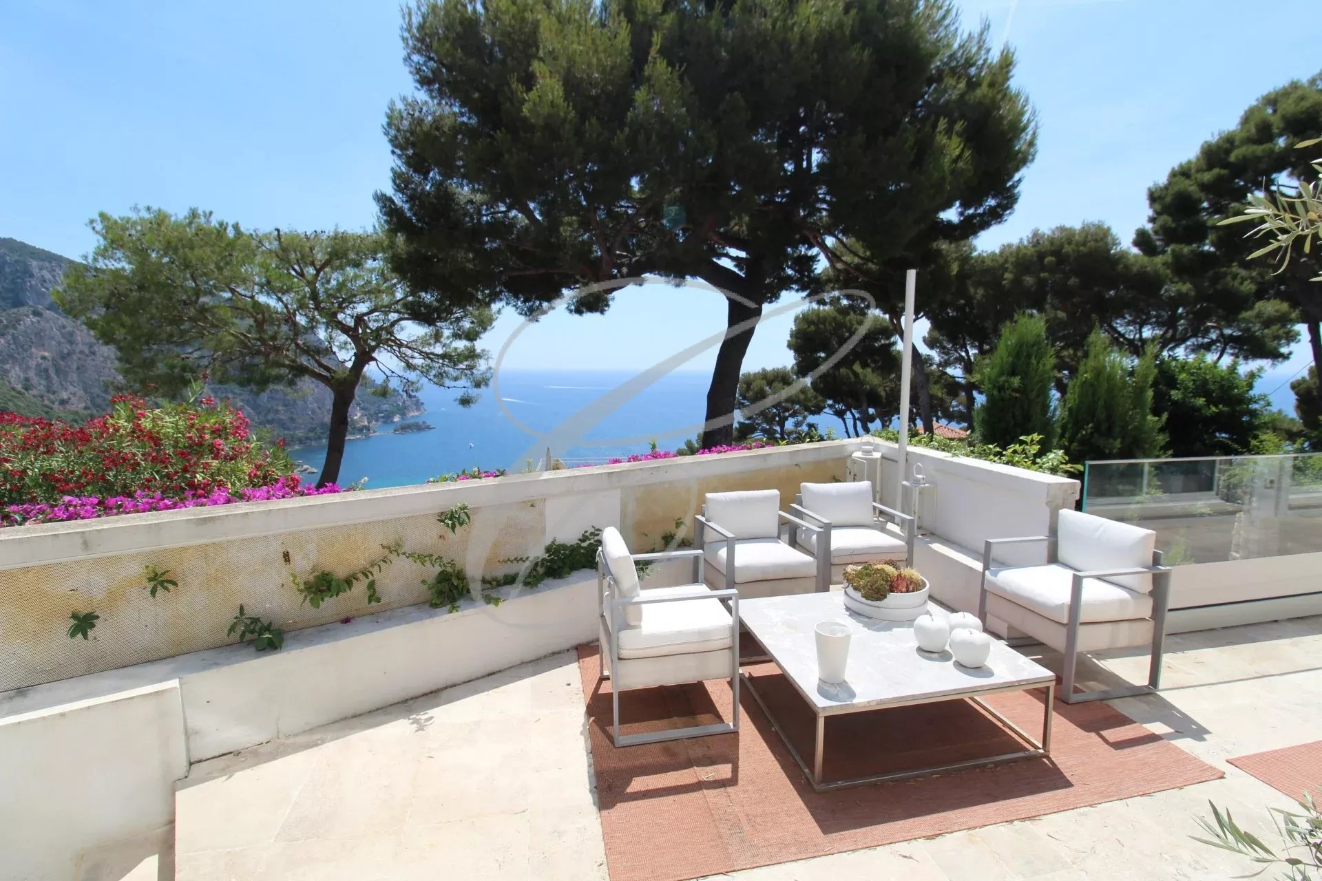 Terrasse d'une villa avec vue sur la mer à Èze, mobilier moderne et plantes environnantes.
