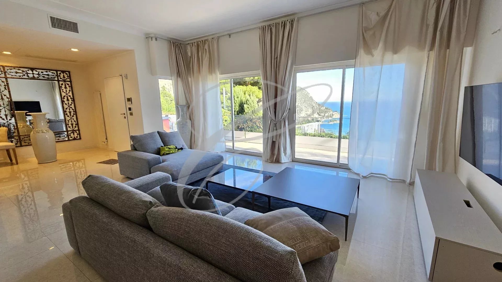 Intérieur d'une villa à Èze avec vue sur la mer, salon lumineux et moderne.