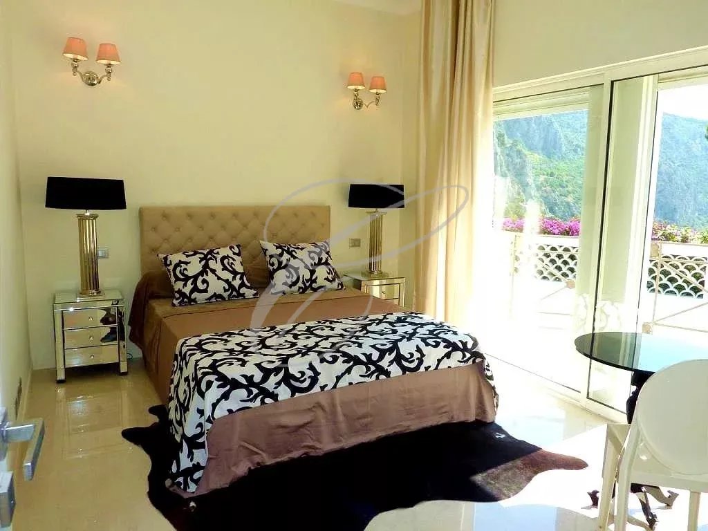 Chambre d'une villa à Èze avec décoration élégante et accès à une terrasse.